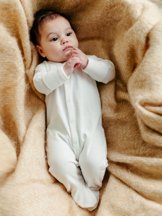 Bebé usando mono de bebé con pie blanco orgánico Drop Needle, con broches frontales – ideal para recién nacidos